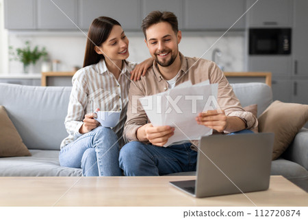 Smiling european couple with coffee and documents near laptop 112720874