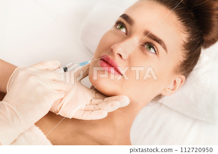 Lip augmentation. Young woman receiving acid injection 112720950