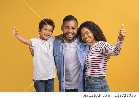 Cheerful black family with preteen son giving thumbs up at camera 112721039
