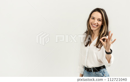 Bright and cheerful young woman with long hair giving a perfect gesture with her hand Bright and cheerful young woman with long hair giving a perfect gesture with her hand 112721040