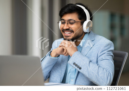 hindu businessman using laptop and headset video calling in office hindu businessman using laptop and headset video calling in office 112721061
