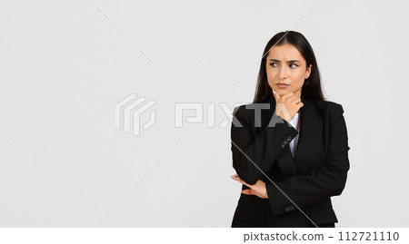Thoughtful businesswoman in suit looking aside at free space 112721110