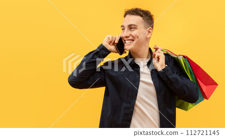 Positive guy with shopping bags talking on phone 112721145