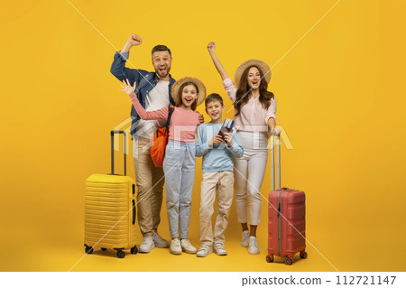 Happy family of four with suitcases and tickets posing on yellow background 112721147