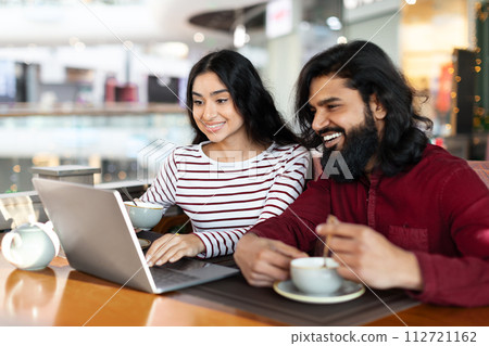 Indian couple using laptop at cozy cafe Indian couple using laptop at cozy cafe 112721162