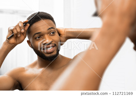 Man combing in bathroom 112721169