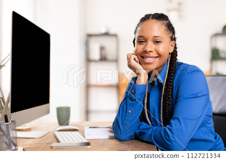 Happy black lady student in blue shirt at computer desk smiling at camera 112721334
