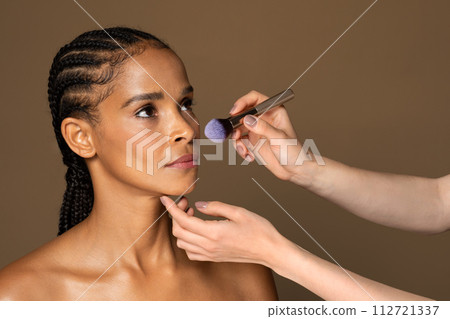 Makeup artist applying blush on african american middle aged model 112721337