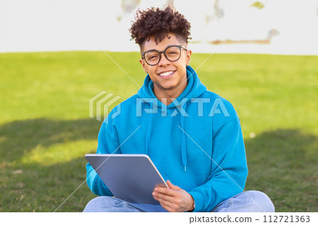 student guy in glasses surfing internet on digital tablet outdoor student guy in glasses surfing internet on digital tablet outdoor 112721363