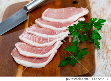 Raw cut pork fillet and parsley on wooden background Raw cut pork fillet and parsley on wooden background 112721397