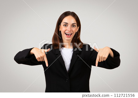 Excited young businesswoman with a beaming smile pointing down at herself with both hands 112721556