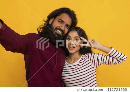 Cute beautiful young indian couple take selfie on yellow 112721566