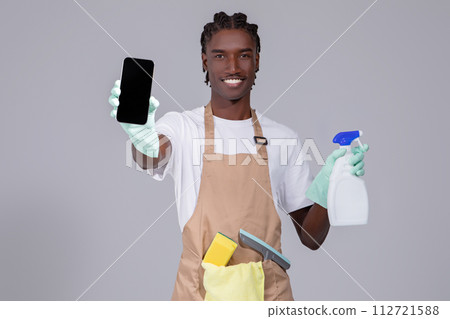 Cleaning Service Ad. Black Man Wearing Apron Showing Blank Smartphone In Hand 112721588