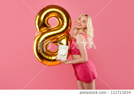 Joyful woman with 8 balloon and gift on pink backdrop 112721634