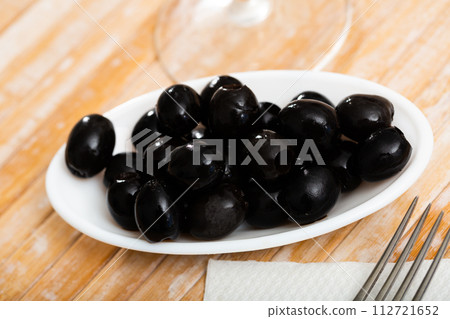 Plate with delicious pitted black olives 112721652
