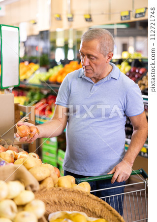 Serious mature male buyer buying onion in hypermarket 112721748