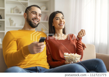 Portrait Of Young Spouses Watching Tv At Home And Eating Popcorn 112721773