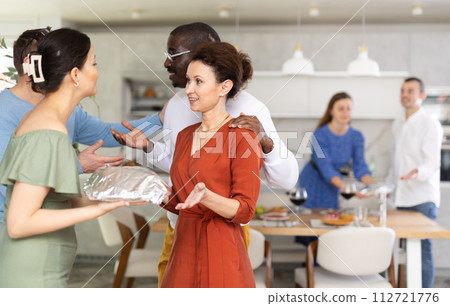 Couple welcoming friends bringing dish for friendly dinner Couple welcoming friends bringing dish for friendly dinner 112721776