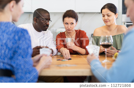 Friends who enjoy lively game of poker and pleasure of tasting fine wine in comfort of their own home Friends who enjoy lively game of poker and pleasure of tasting fine wine in comfort of their own home 112721808