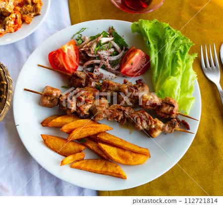 Lamb shish kebab with lettuce, tomatoes and French fries closeup. Turkish cuisine 112721814