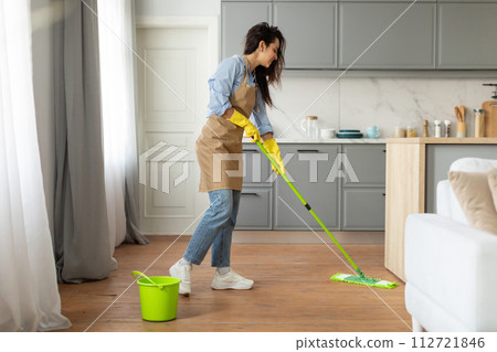 Woman mopping floor in bright kitchen interior 112721846