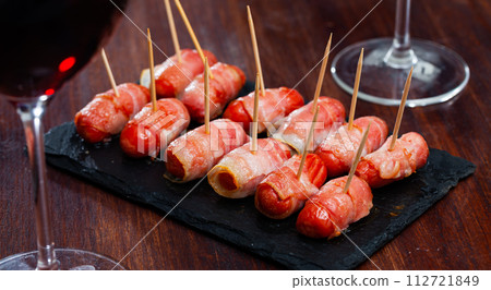 Spanish tasty meal rolled in bacon sausages at plate Spanish tasty meal rolled in bacon sausages at plate 112721849