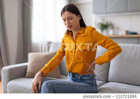 Young woman with back pain on couch 112721884