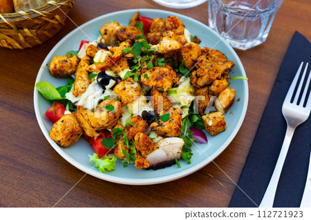 Traditional dish of American cuisine is a warm Caesar salad with fried chicken and champignons 112721923