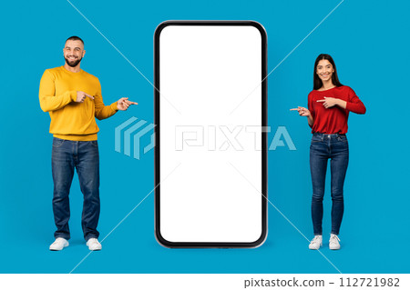 Place For Ad. Happy Young Caucasian Couple Pointing At Big Blank Smartphone 112721982