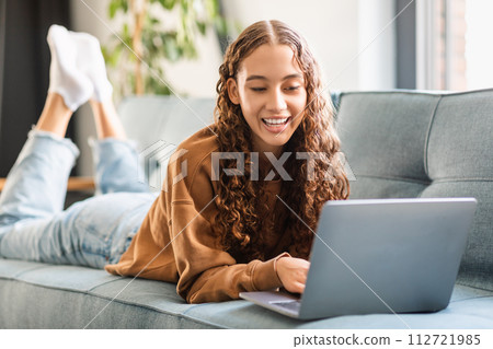 Happy modern adolescent girl enjoys e-learning with laptop at home 112721985