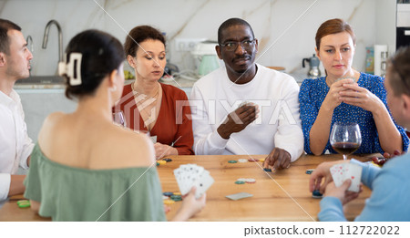 African American man playing poker with friends at kitchen table African American man playing poker with friends at kitchen table 112722022