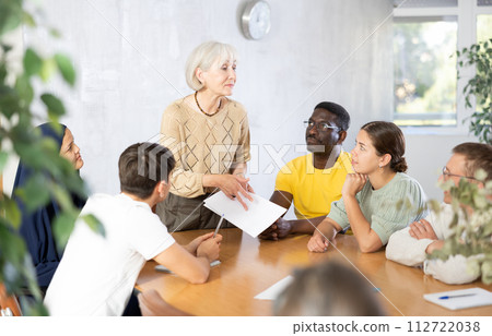 Group of multinational people discussing documents at table Group of multinational people discussing documents at table 112722038