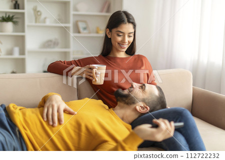 Happy young couple relaxing on couch in cozy home atmosphere 112722232