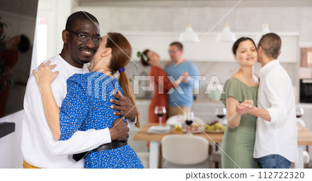 Friends party - men and women of different nationalities dancing slow dance at home Friends party - men and women of different nationalities dancing slow dance at home 112722320