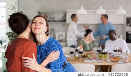 Smiling woman giving greeting kiss to bestie at dinner party Smiling woman giving greeting kiss to bestie at dinner party 112722398