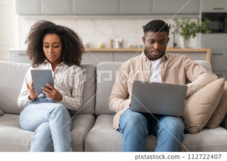 Modern millennial black couple browsing on laptop and tablet indoor 112722407