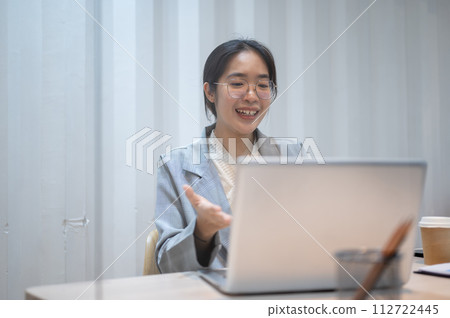 A confident Asian businesswoman is having an online meeting with her client, working in her office. 112722445