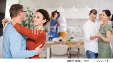 Friends party - men and women of different nationalities dancing slow dance at home Friends party - men and women of different nationalities dancing slow dance at home 112722510