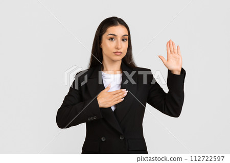 Serious young businesswoman taking oath Serious young businesswoman taking oath 112722597