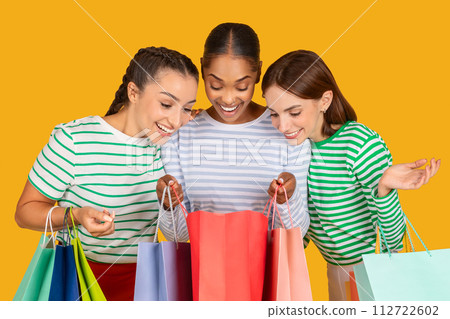 Closeup of multiracial ladies looking inside shopping bags Closeup of multiracial ladies looking inside shopping bags 112722602
