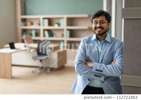 Confident successful Indian businessman stands crossing hands in modern office 112722863