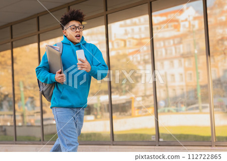 Brazilian student guy with backpack and phone rushes through city Brazilian student guy with backpack and phone rushes through city 112722865