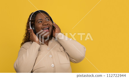 Positive overweight african american woman listening to her favorite song Positive overweight african american woman listening to her favorite song 112722944