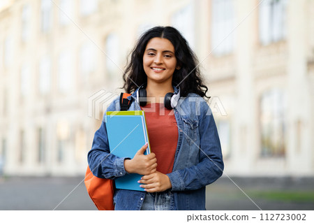 Positive middle eastern lady student posing at university campus Positive middle eastern lady student posing at university campus 112723002