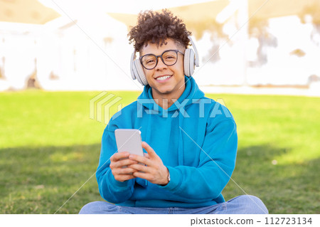 guy enjoys music or audiobook in headphones using smartphone outdoor guy enjoys music or audiobook in headphones using smartphone outdoor 112723134