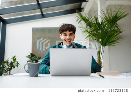 Laughing freelancer man with headphones at laptop 112723138