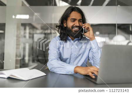 Smiling millennial eastern man manager have phone conversation with client Smiling millennial eastern man manager have phone conversation with client 112723143