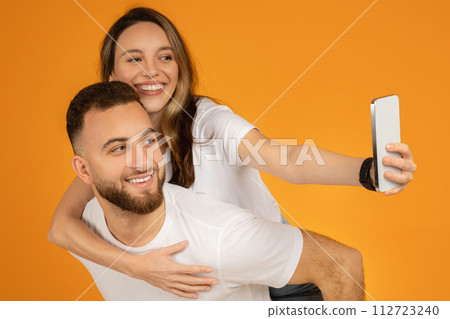 Cheerful young couple in white shirts taking a selfie with a smartphone 112723240