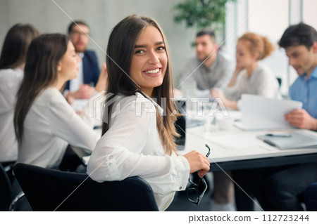 Positive secretary smiling to camera during meeting Positive secretary smiling to camera during meeting 112723244