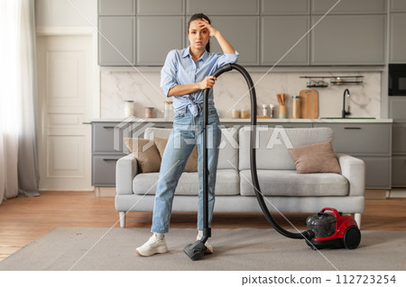 Exhausted woman with vacuum cleaner in home setting Exhausted woman with vacuum cleaner in home setting 112723254